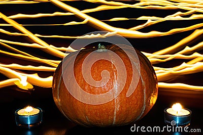 Orange pumpkin and two lighted tea candles on background of fire lines. Halloween concept Stock Photo