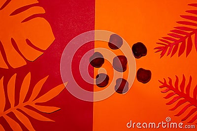 orange-red background with jungle leaf of the same color between them cherry-shaped flowers, creative summer design Stock Photo