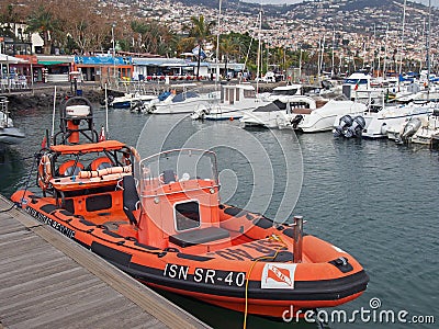 An orange rescue boat belonging to the Portuguese lsn national lifeboat service moored in the marina with yachts and waterside Editorial Stock Photo