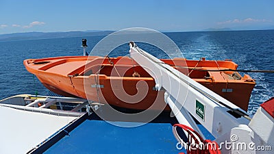 Orange rescue boat on a passenger ship cruising in the Aegean Sea on a sunny day Editorial Stock Photo