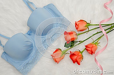 Orange roses and blue bodice with lace on white fur. Fashionable concept. Top view, close-up Stock Photo