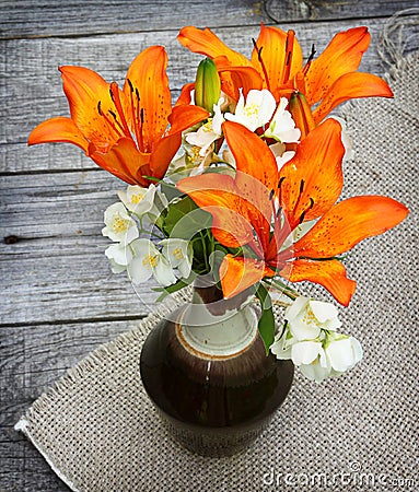 Orange saffron lilies and jasmine flowers on wooden table Stock Photo