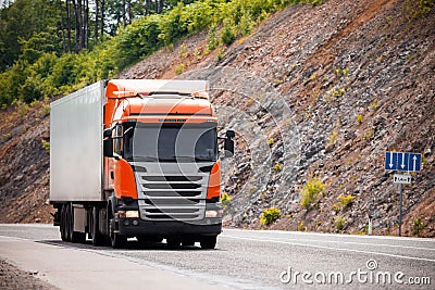 Orange truck moving by a road Stock Photo