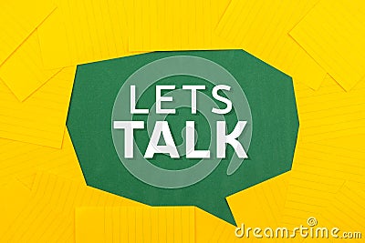 Orange sheets of paper lie on a green school board and form a chat bubble with text let`s talk Stock Photo