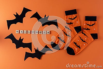 Orange socks with bats. Clothing costume for Halloween party. Cheerful bright multicolored sock top view. Stock Photo