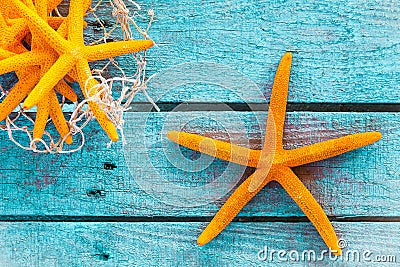 Orange starfish on turquoise boards with fish net Stock Photo