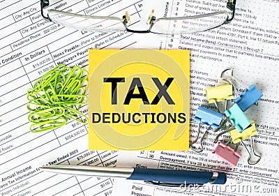 Orange sticker with text Tax Deductions. Colored stationery clips, green paper clips and eyeglasses Stock Photo