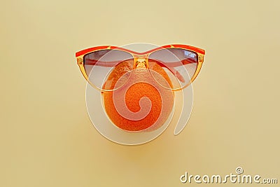 Orange in sunglasses on pastel yellow paper, trendy flat lay. su Stock Photo