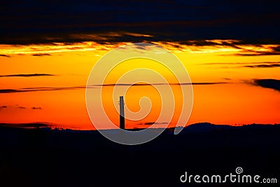 industrial chimney in orange sunrise light Stock Photo