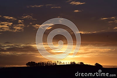 orange sunrise sky above a dark hill Stock Photo