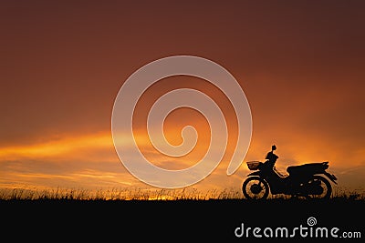Orange sunset sky. Silhouette motorcycle in sunset landscape backdrop Stock Photo