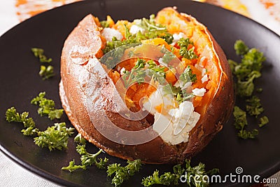 Orange sweet potatoes baked with cream cheese and parsley close-up on a black plate. horizontal Stock Photo