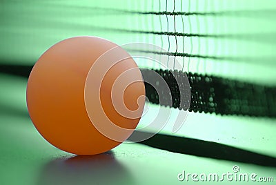 Orange table tennis ball on green table with net Stock Photo