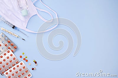 Orange tablets in the package, an injection syringe, a thermometer, a medical face shield and a sanitizer. Medical Stock Photo