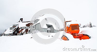 Orange tractor in front of a house buried in snow Stock Photo