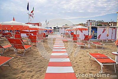 Orange umbrellas and chaise lounges on the beach of Rimini in It Editorial Stock Photo