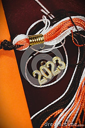 Orange, white, and brown graduation tassel and gold 2023 charm laying on seat Stock Photo
