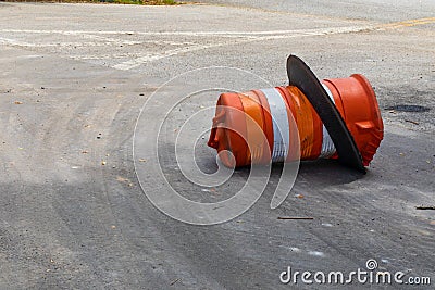 Orange and white traffic barrel knocked over on its side, traffic accident reckless driving Stock Photo