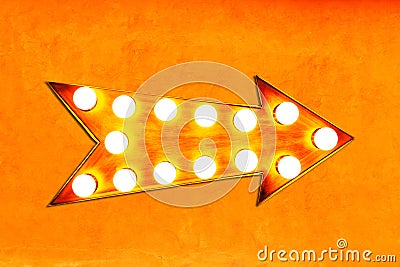 Orange, yellow and reddish color vintage bright and colorful illuminated metallic display arrow sign on orange wall Stock Photo