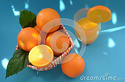 Oranges and freshly squeezed orange juice on a blue background with bright sun highlights Stock Photo