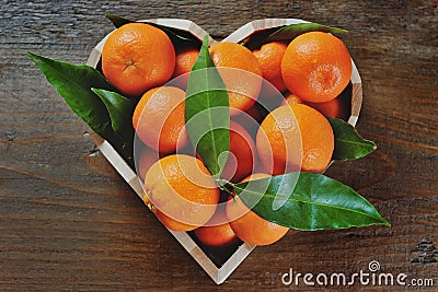 Oranges in a heart shaped box on a wooden background Stock Photo