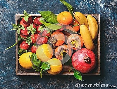 Oranges, lemons, pomegranate, bananas, strawberries and persimmon in wooden box Stock Photo