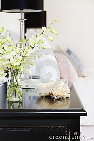 Orchids in vase on pretty bedside table vertical Stock Photo