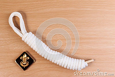 Orderliness white scout rope with vintage boy scouts badge on wooden table. Stock Photo