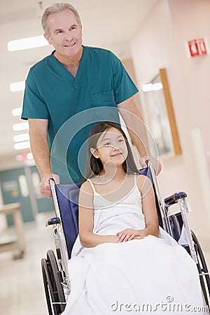 An Orderly Pushing A Little Girl In A Wheelchair Stock Photo