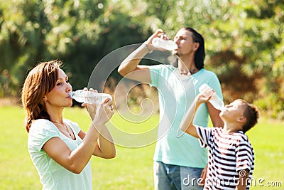 Ordinary family of three drinking from bottles Stock Photo