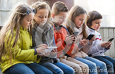 Ordinary kids sitting with mobile devices Stock Photo