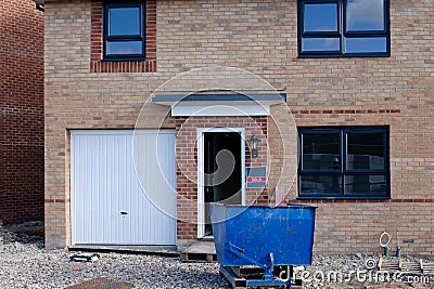 An ordinary new house for sale and blue recycling skip in front of it Stock Photo