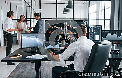 Ordinary office day. Team of stockbrokers works in indoors with many display screens Stock Photo