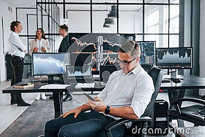 Ordinary office day. Team of stockbrokers works in indoors with many display screens Stock Photo