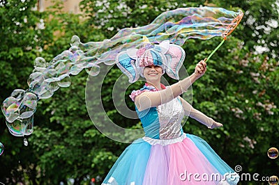 Orel, Russia, May 26, 2019: Twin Festival. Smiling woman in bright unicorn costume making big soap bubbles Editorial Stock Photo