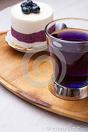 Organic Butterfly pea, clitoria or Blue pea flower herbal tea. Thai blue tea. served with blueberry cake on wooden tray. close Stock Photo