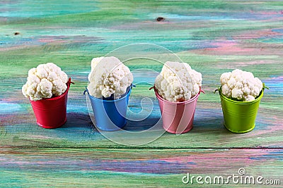 Organic cauliflower in colored buckets, wooden background. Authentic lifestyle image. Flat lay. copy space Stock Photo