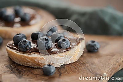 Organic chocolate hazelnut spread with fresh blueberries on ciabatta slices on wood board Stock Photo