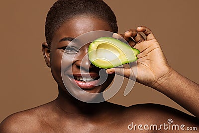 Organic Cosmetics. Black Female With Short Hair Covering Eye With Avocado Half Stock Photo