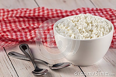 Organic curd cottage cheese in a white ceramic bowl and red napkin on a wooden table Stock Photo