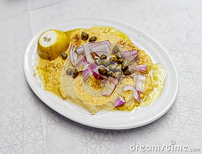 Organic fava split peas puree Greek gourmet plate with onion, capers, black pepper, lemon and olives. Stock Photo