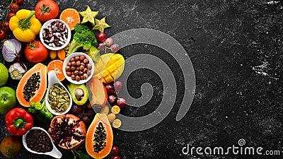 Organic food. Fruits, vegetables, beans and nuts on a black stone background. Top view. Stock Photo