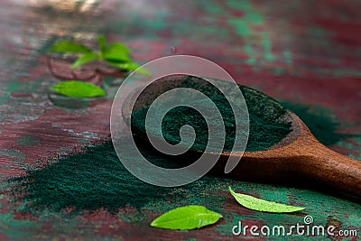 Organic green spirulina powder top view on wooden spoon background. Super foods, Stock Photo