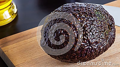Organic Haas avocado on cutting board and oil ready to cooking. Stock Photo