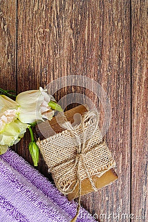 Organic handmade soap, purple sauna towel and flowers on walnut tree background, layout with free text space Stock Photo