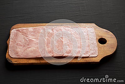 Organic Jamon Cocido Extra on a rustic wooden board on a black surface, low angle view Stock Photo