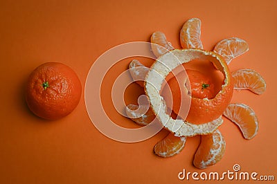 Organic mandarin wedges arranged in a circle with spiral peel and one whole mandarin on an orange paper background Stock Photo