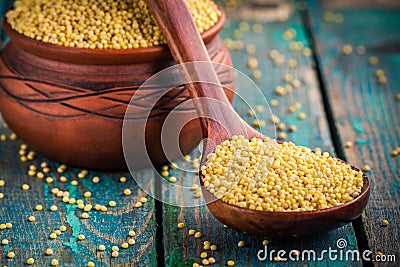 Organic millet seeds in a spoon and a ceramic bowl closeup Stock Photo