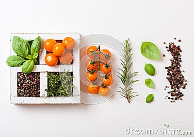 Organic Orange Rapture Cherry with basil and pepper and rosemary in white wooden box on stone kitchen background. Cooking concept Stock Photo