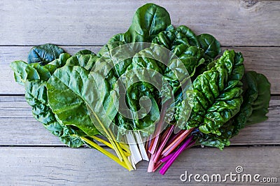 Organic rainbow chard: spray-free leafy greens in fan arrangement on rustic wooden background Stock Photo